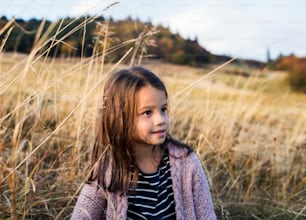 A happy small girl standing in autumn nature. Copy space.