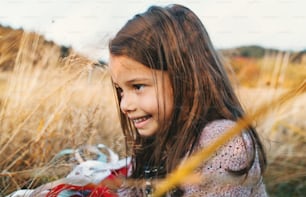 Una bambina felice che gioca con un aquilone arcobaleno nella natura autunnale.