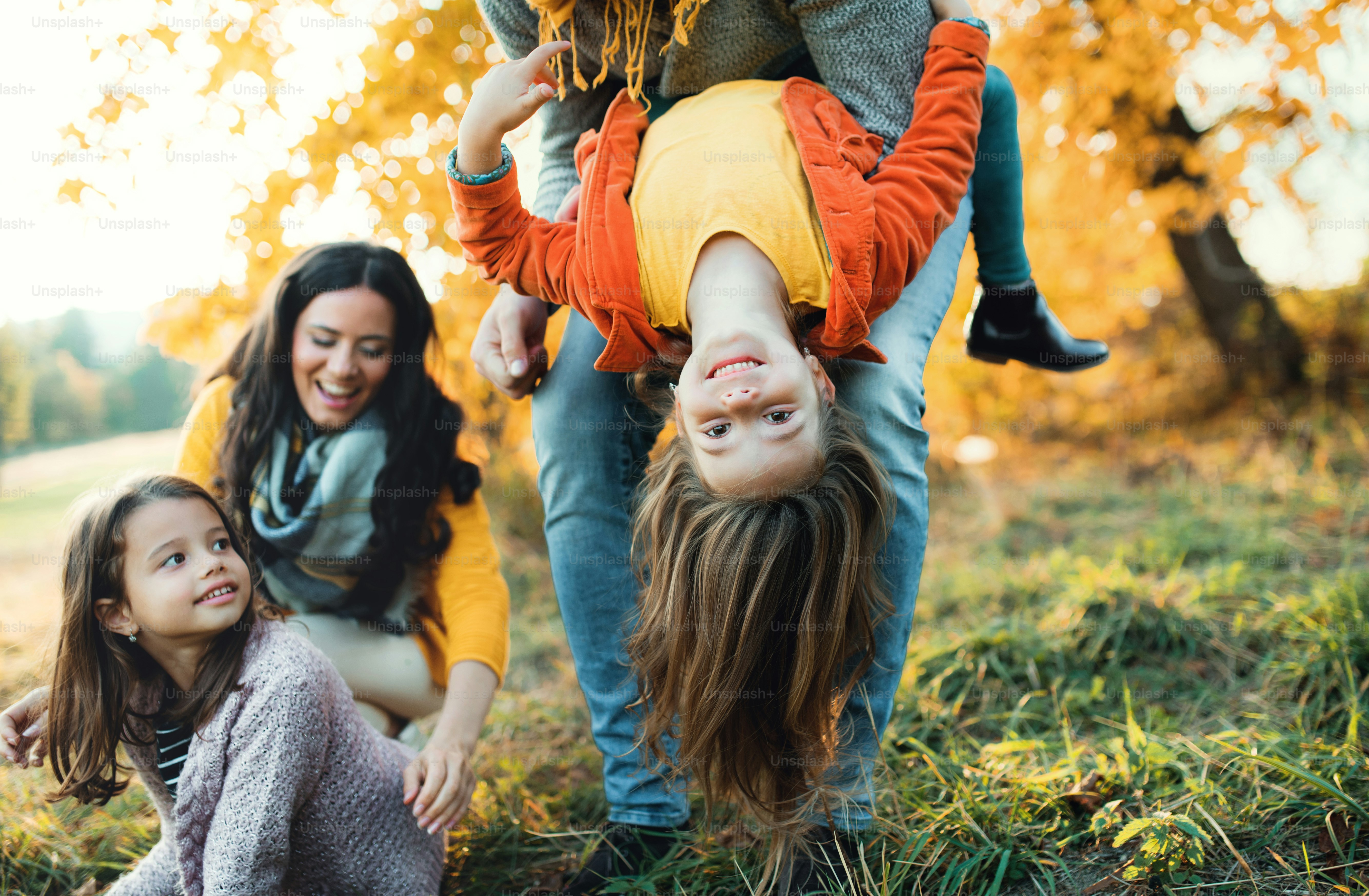 Um retrato de uma família jovem feliz com duas crianças pequenas na natureza do outono, se divertindo.