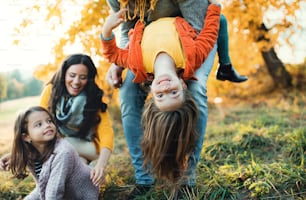 가을 자연에서 두 명의 어린 아이와 함께 즐거운 시간을 보내는 행복한 젊은 가족의 초상화.