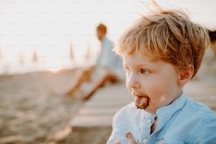A small toddler boy on beach on summer holiday, sticking out tongue. Copy space.