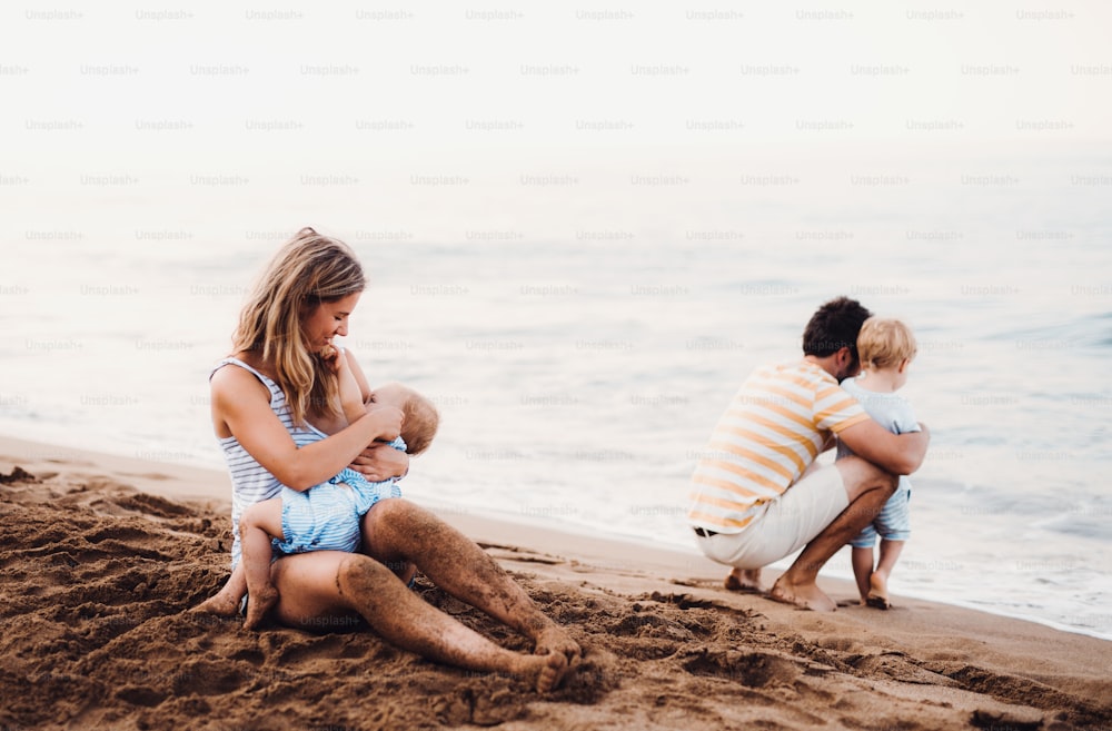 A young family with two toddler children on beach on summer holiday.