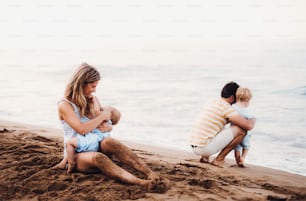 Una familia joven con dos niños pequeños en la playa durante las vacaciones de verano.