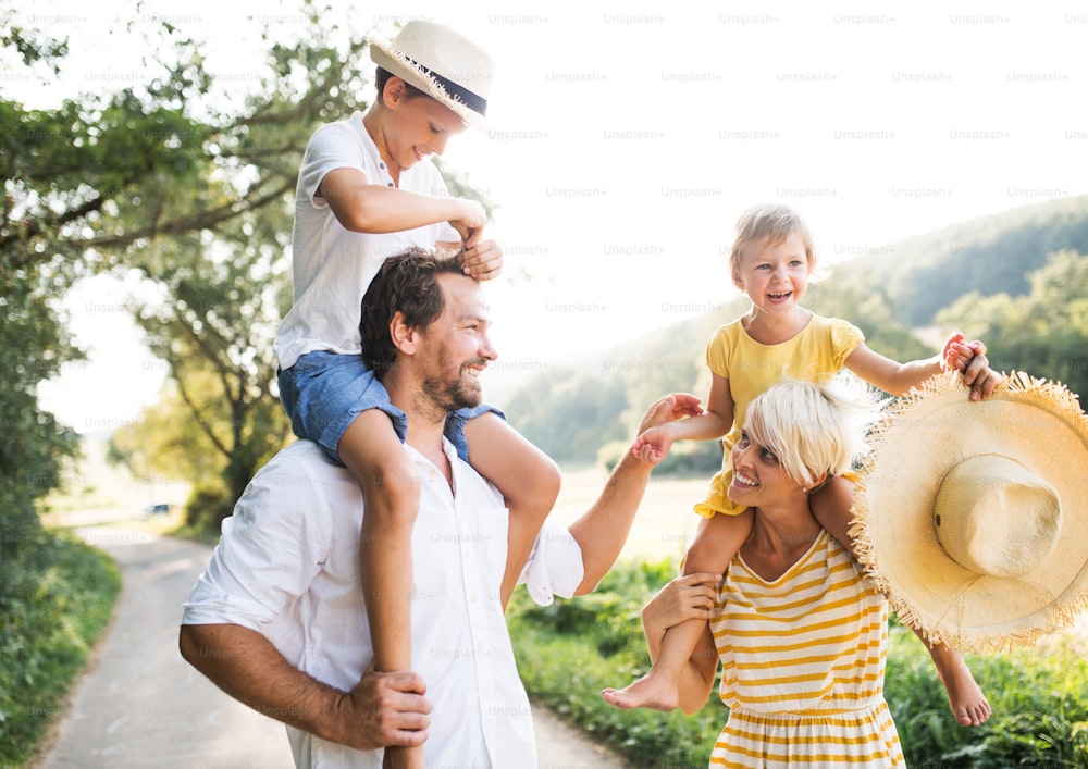 Familia joven feliz con niños pequeños que pasan tiempo juntos al aire libre en la naturaleza verde del verano.