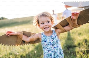 A cute small girl playing on a meadow in nature, flying with wings.
