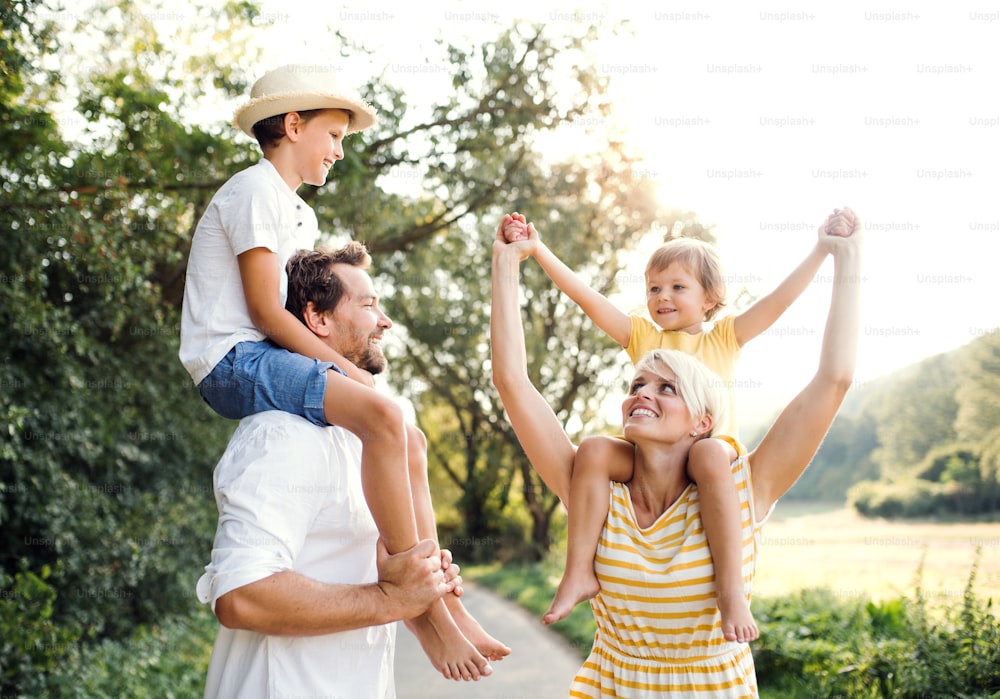 Família jovem feliz com crianças pequenas que passam o tempo juntos ao ar livre na natureza verde do verão.