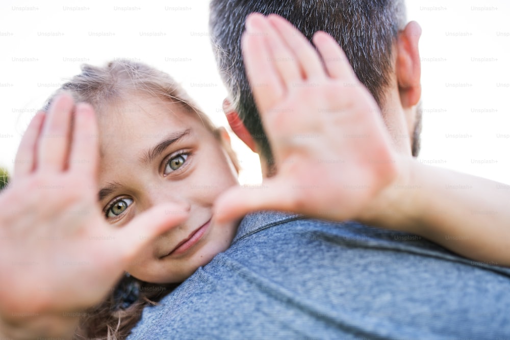 Unrecognizable father with a small daughter having fun in sunny spring nature.