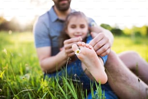 Unrecognizable father with a small daughter having fun in sunny spring nature.