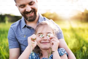 Padre con una hija pequeña divirtiéndose en la soleada naturaleza primaveral.