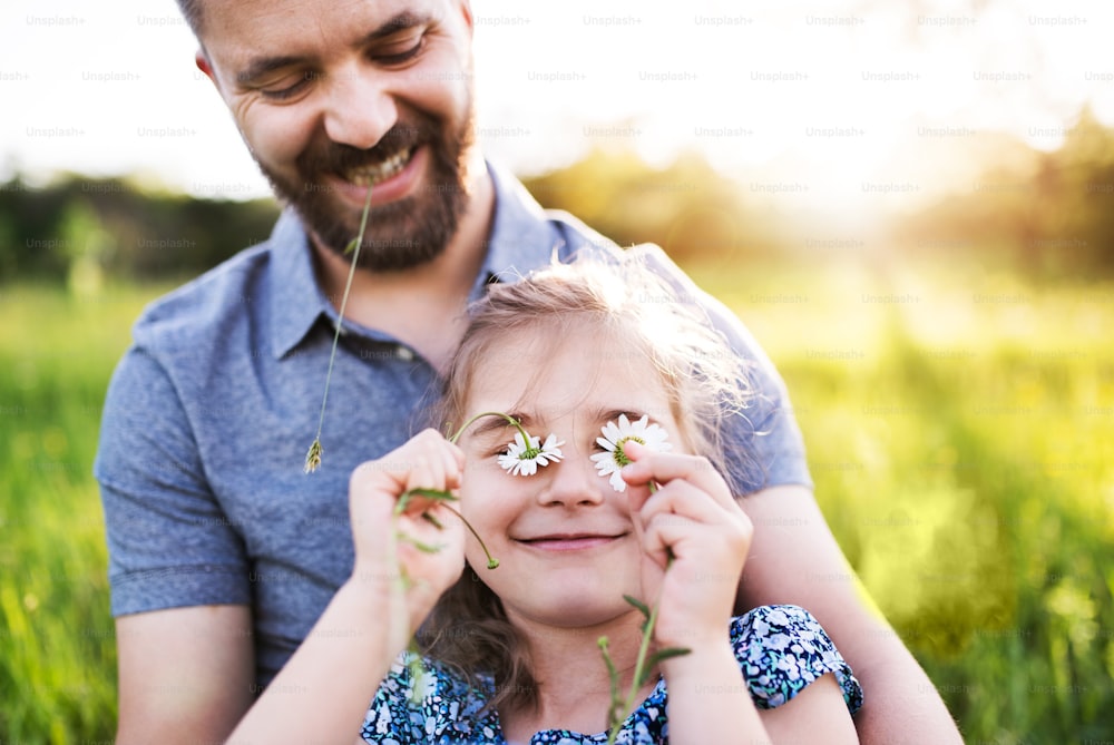 Vater mit einer kleinen Tochter, die sich in der sonnigen Frühlingsnatur amüsiert.