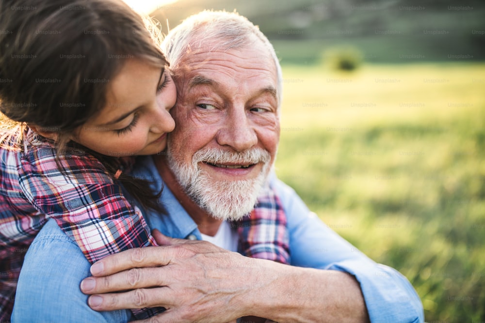 A cheerful small girl with grandfather outside in spring nature, having fun. Copy space.