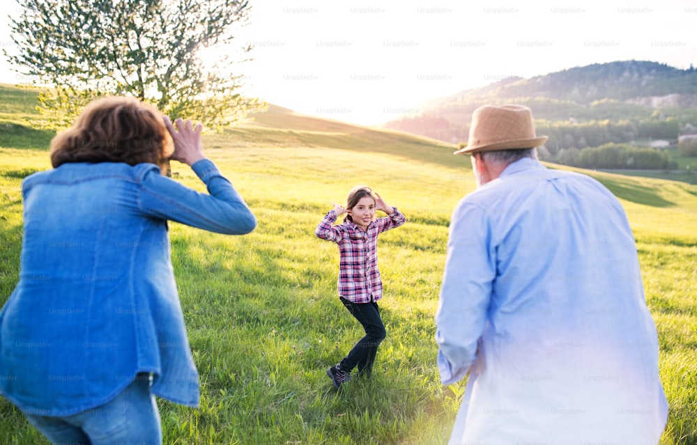 Uma garotinha feliz com seus avós mais velhos se divertindo ao ar livre na natureza.