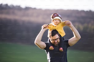 A handsome father with his toddler daughter outside in green sunny spring nature. Copy space.