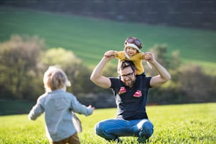 Un padre con sus hijos pequeños divirtiéndose afuera en la naturaleza primaveral.