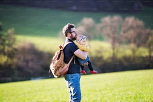 A handsome father with his toddler daughter outside in green sunny spring nature.