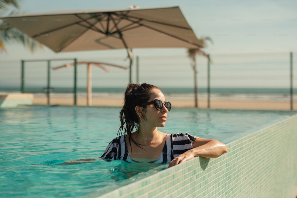 uma mulher sentada em uma piscina ao lado da praia