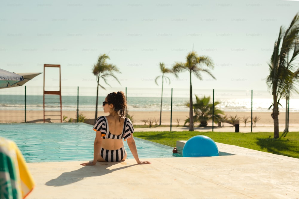 a woman sitting on the edge of a swimming pool