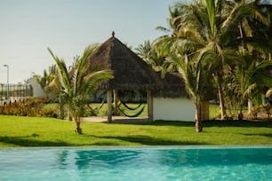 a small hut with a thatched roof next to a pool