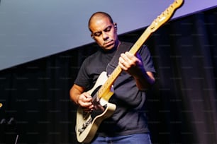 a man playing a guitar while standing in front of a microphone
