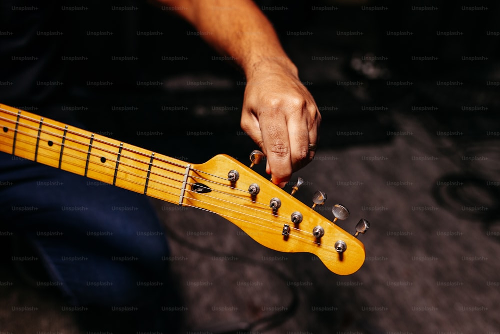 Una persona sosteniendo una guitarra amarilla en la mano