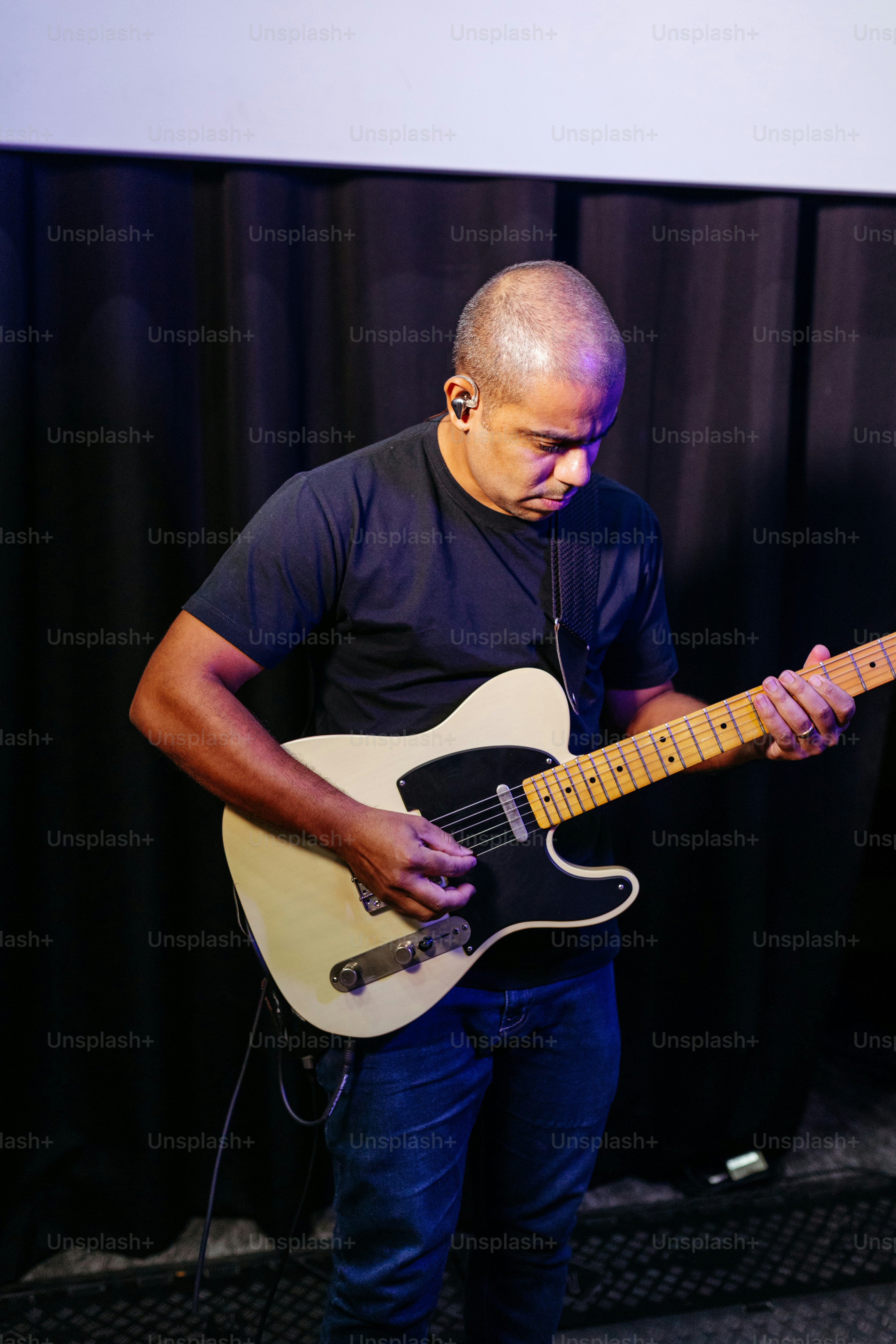 a man playing a guitar in front of a microphone