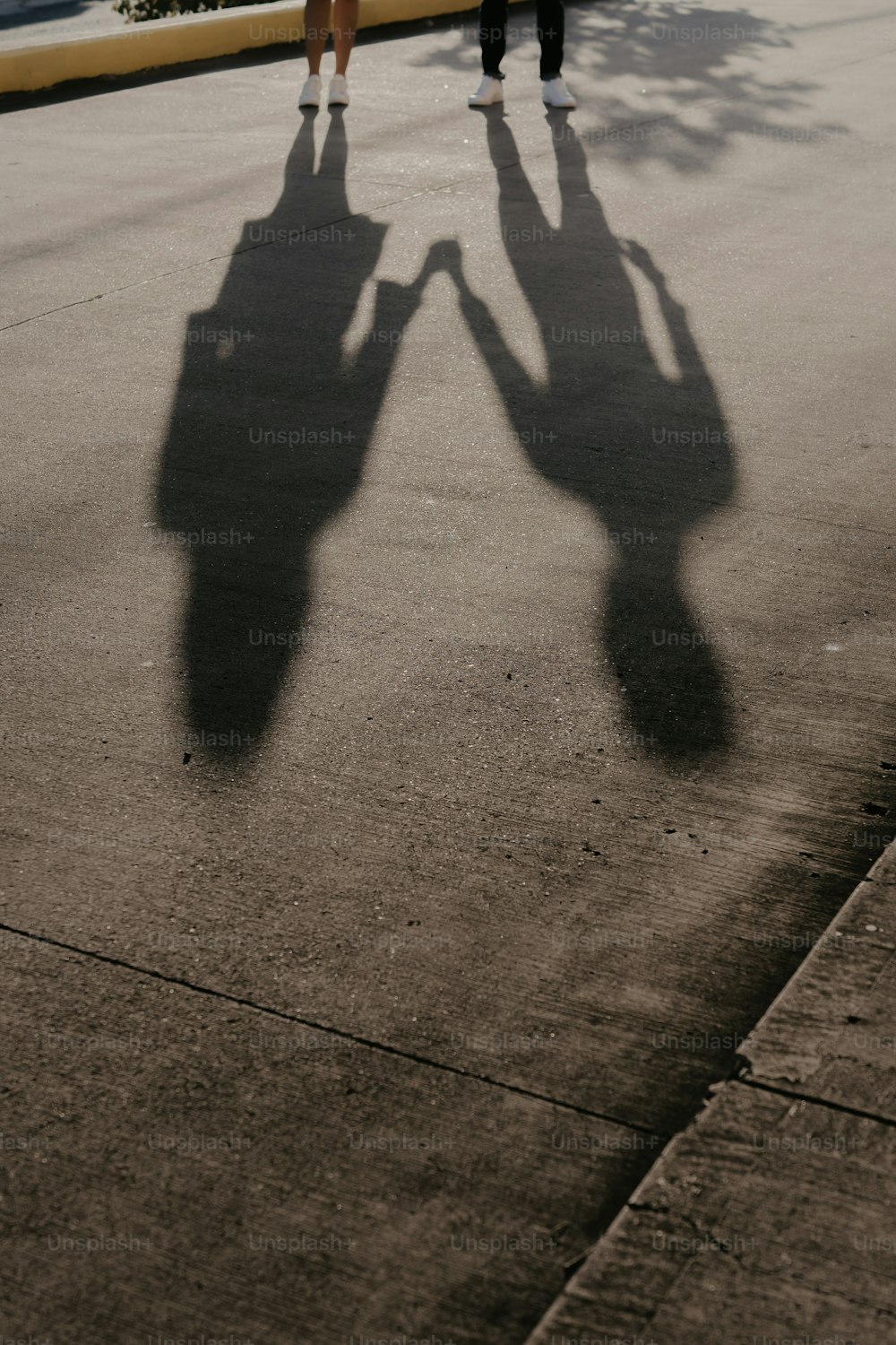 a shadow of two people walking down a street