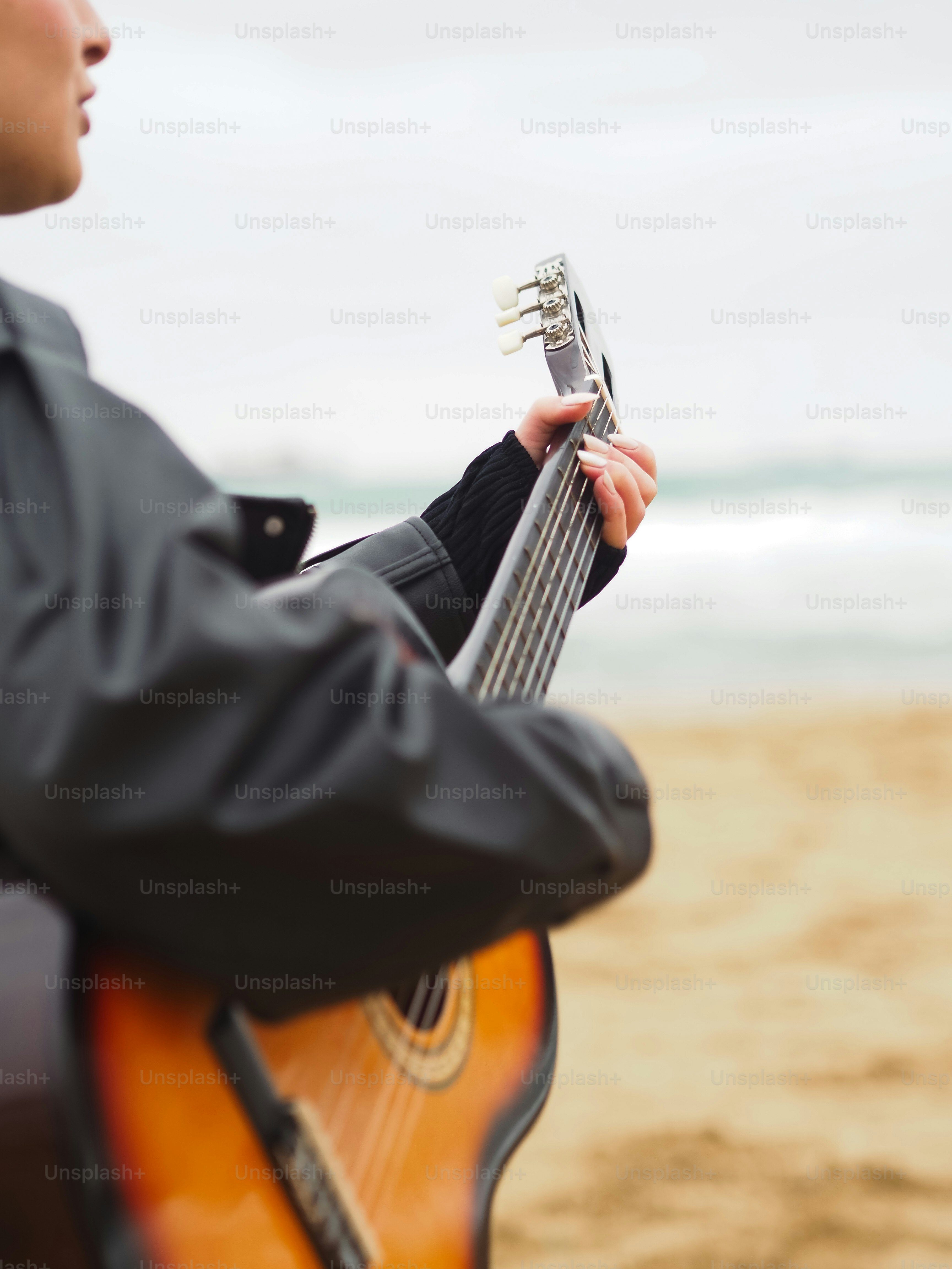 Un hombre sosteniendo una guitarra en la playa