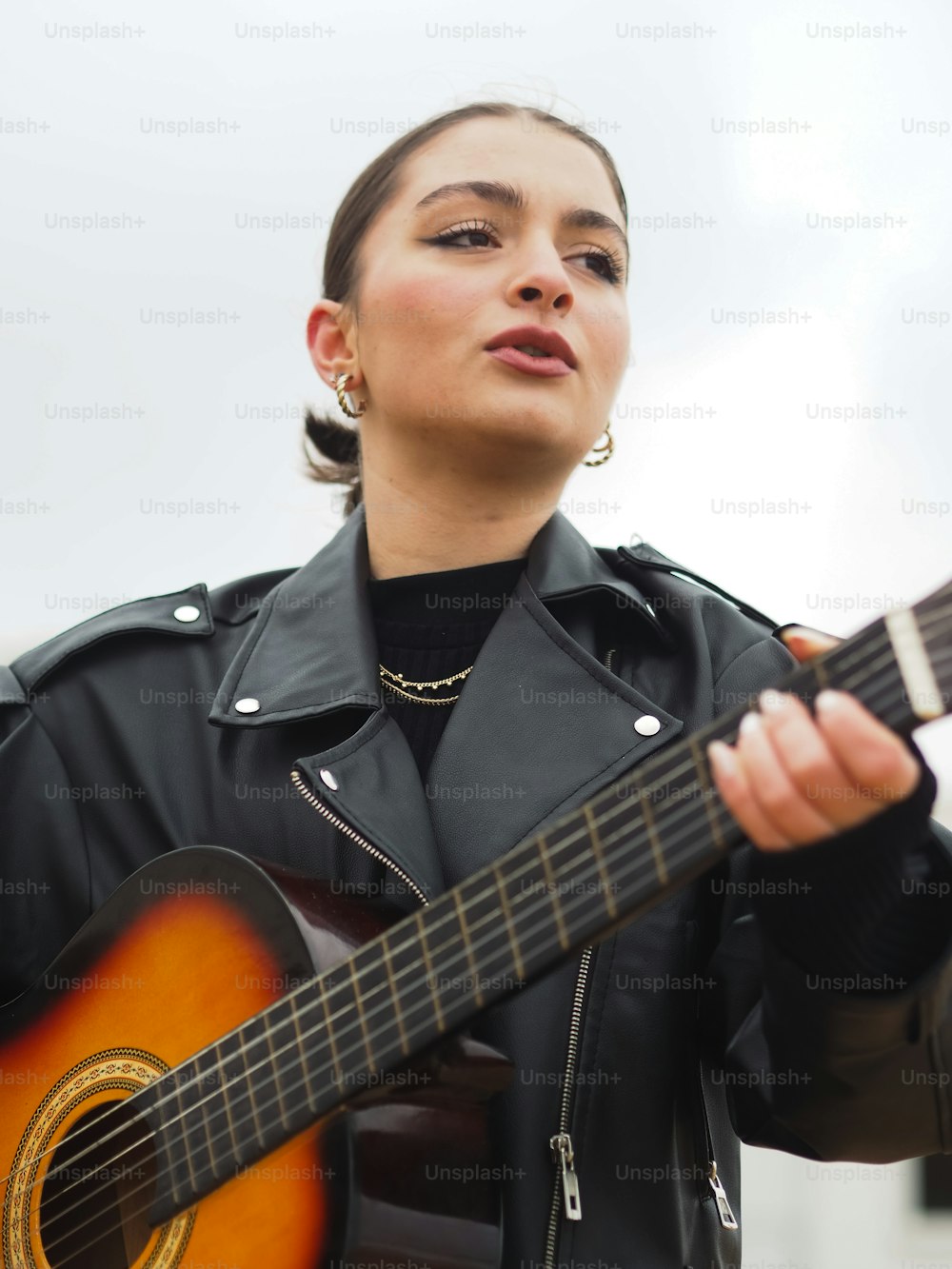 a woman in a black jacket holding a guitar