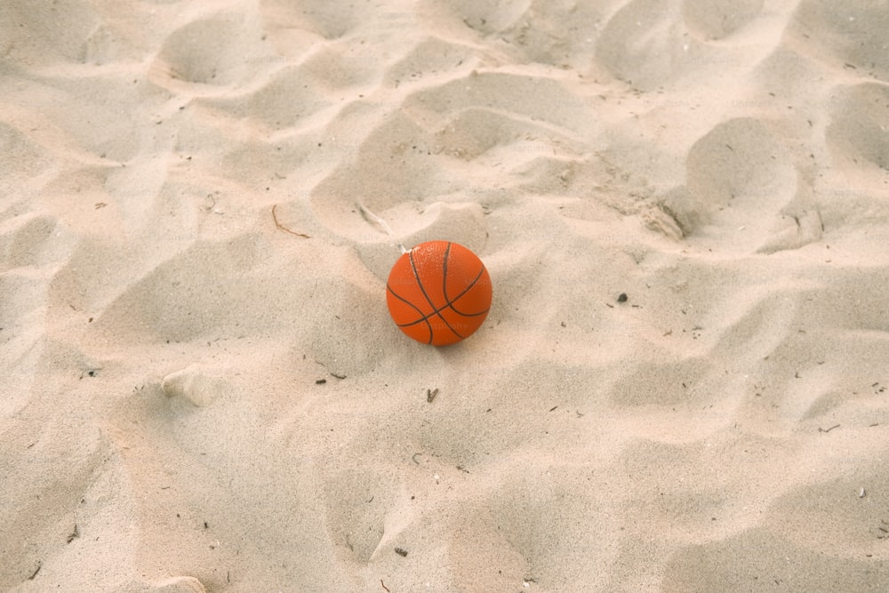 Una pelota de baloncesto sentada en la cima de una playa de arena