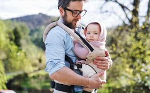Um pai com sua filha pequena em um carrinho de bebê do lado de fora em uma caminhada de primavera. Espaço de cópia.
