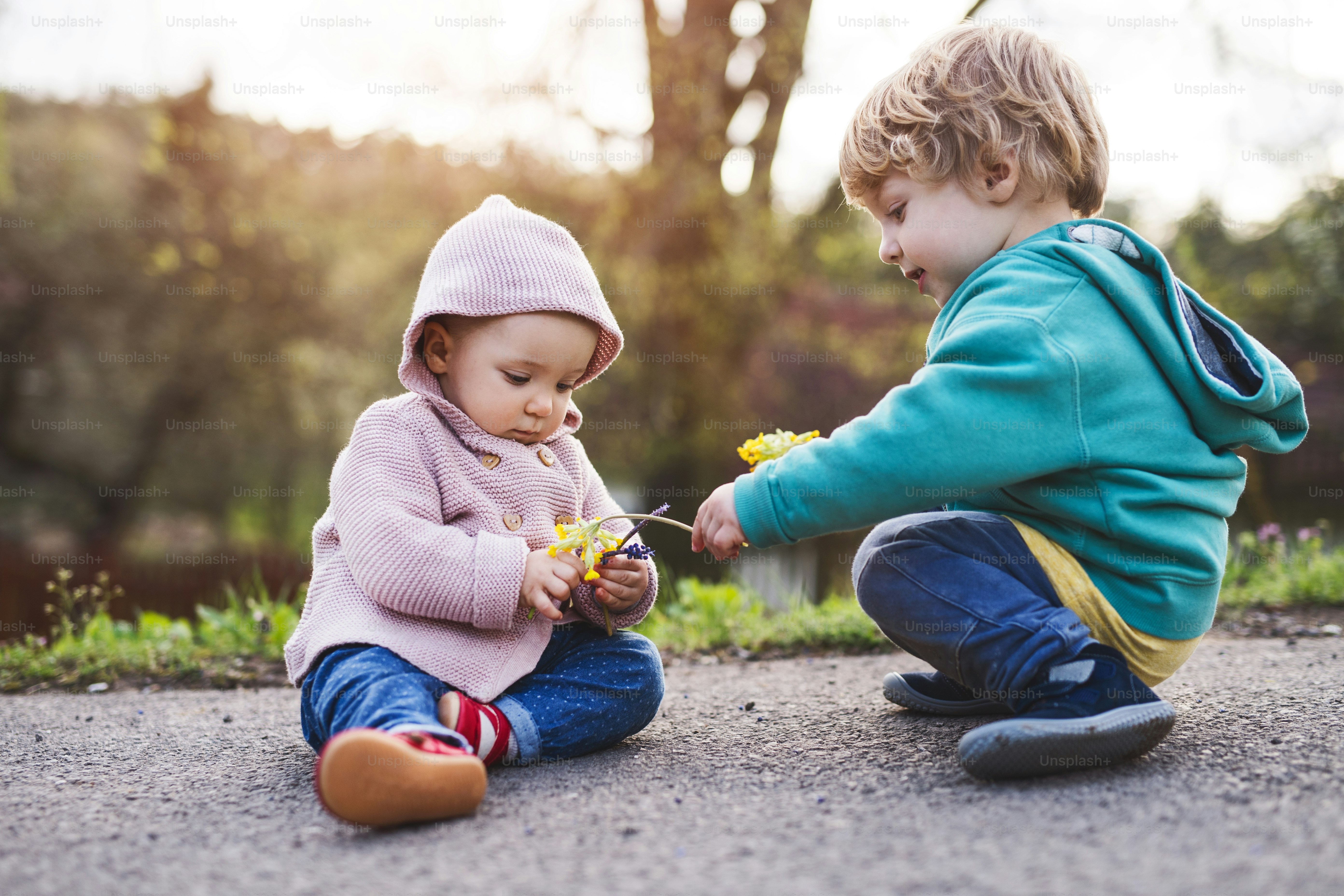 Un père méconnaissable avec ses deux enfants en bas âge dehors lors d’une promenade printanière ensoleillée.