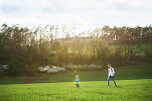 어린 아들과 함께 푸른 햇살이 내리쬐는 봄 자연 속에서 산책을 하는 아버지.