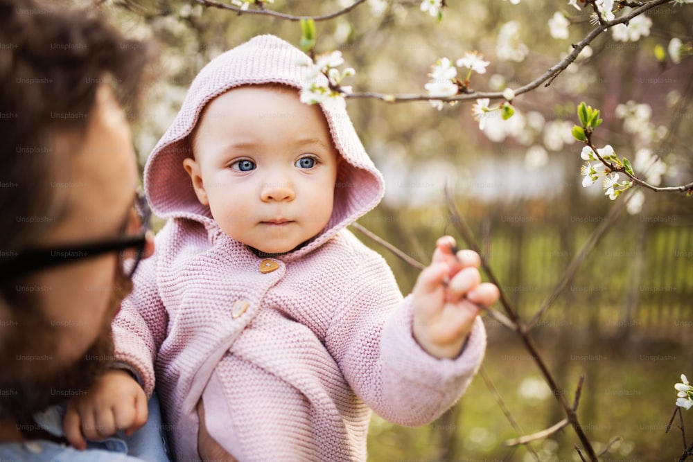 緑の日当たりの良い春の自然の中で外にいる幼児の娘を持つ認識できない父親。