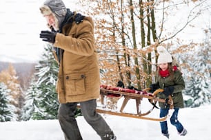 Avô sênior e uma menina pequena se divertindo na neve em um dia de inverno.