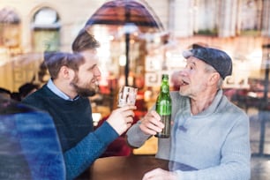 Un père âgé et son jeune fils buvant de la bière dans un pub.