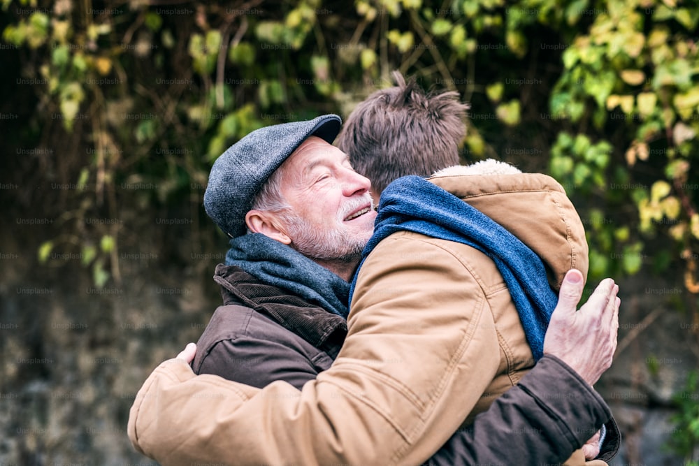 Il padre anziano e il suo giovane figlio durante una passeggiata in città, abbracciati.