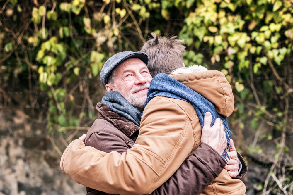 Senior father and his young son on a walk in town, hugging.