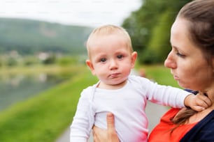 Cute little boy with his mother in nature. Young woman holding her toddler boy. Summer time.