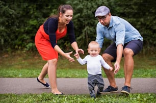 Cute little boy making first steps in nature. Young family spending time in nature. Summer time.