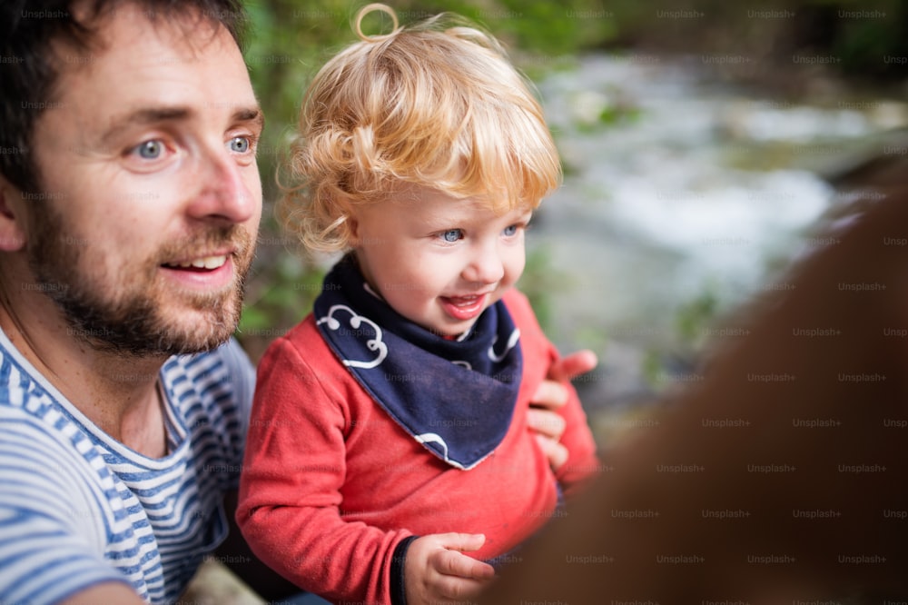 Young father with happy little boy at the river, summer day.