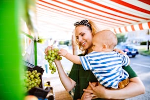 Young mother with her baby boy shopping at the outdoor market.