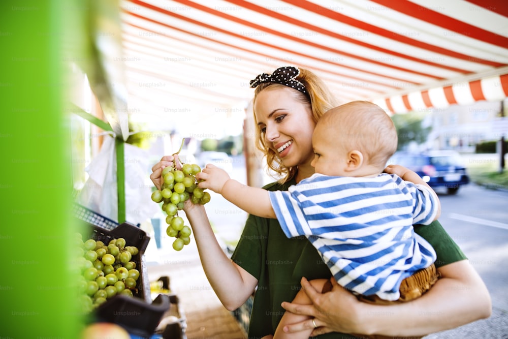 Young mother with her baby boy shopping at the outdoor market.