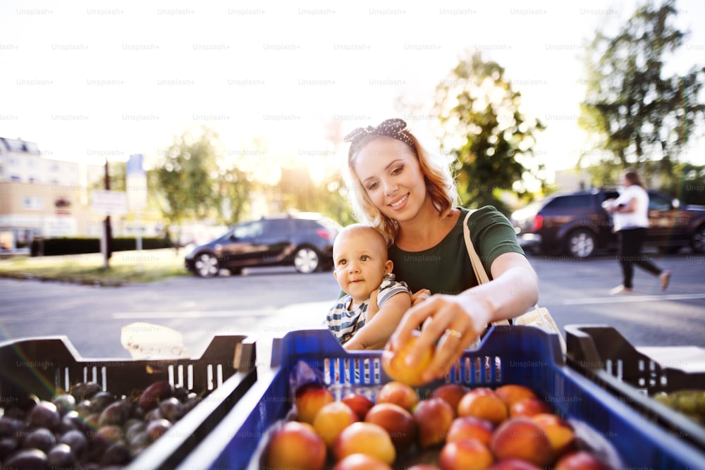 Young mother with her baby boy shopping at the outdoor market.