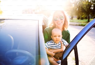 La joven madre sostiene a su pequeño bebé en los brazos al subir al auto.