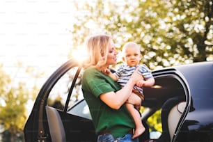 어린 아기를 품에 안고 차에 타는 젊은 엄마.