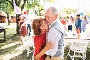 Ein älteres Paar tanzt auf einer Gartenparty oder Familienfeier draußen im Hinterhof.