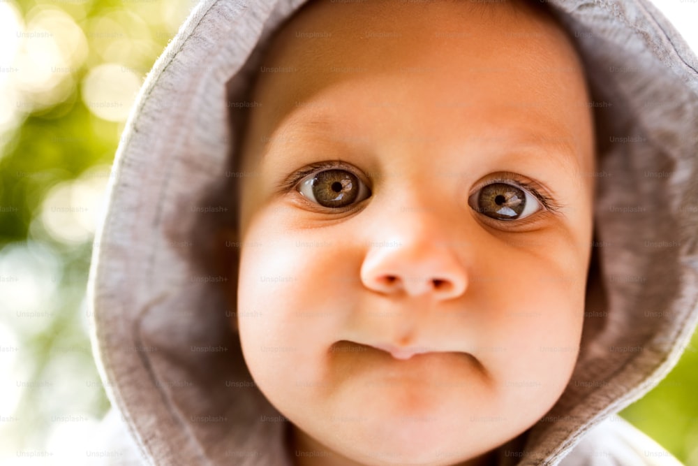 Portrait of a cute baby boy outside in a garden. Close up.