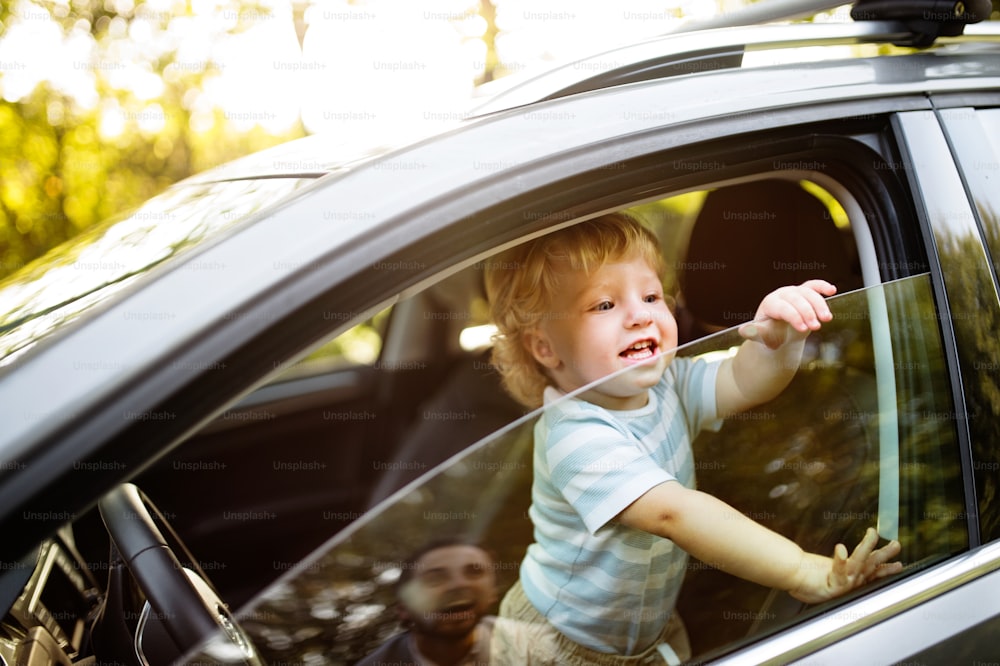 Cute little boy playing in the car, looking out of the window.