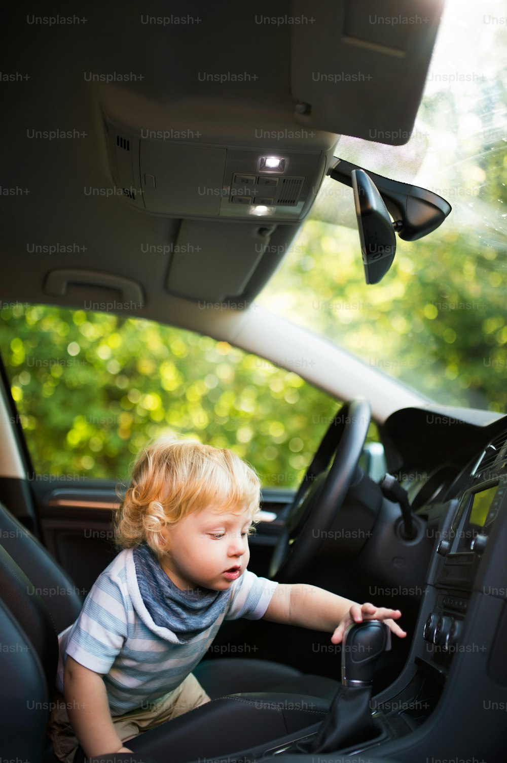 차에서 놀고 있는 귀여운 소년이 운전하는 척한다.