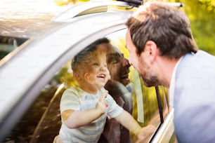 Garotinho bonito no carro olhando para seu pai. Filho acenando para o pai.